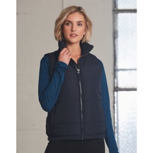 A navy heavy quilted vest with a high collar, featuring a zip closure, worn over a blue long-sleeve top.