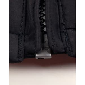 A close-up of a black heavy quilted jacket, highlighting the zip and stitching details. The jacket features a logo.
