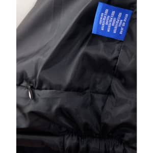 A black heavy quilted jacket featuring a zippered pocket and a label with branding.