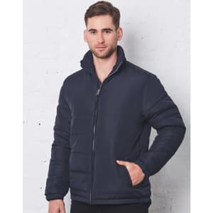 A navy heavy quilted puffer jacket with a zippered front and high collar, modelled by a man against a white wall.