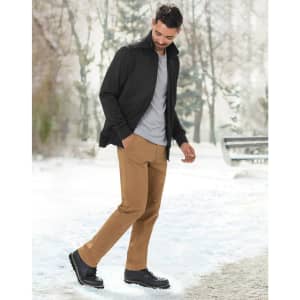 A man wearing a black jacquard fleece jacket, grey shirt, and tan pants, walking in a snowy outdoor setting.