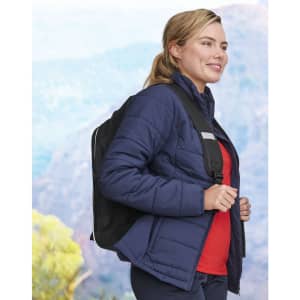 A navy insulated puffer jacket with a fitted cut, worn by a woman carrying a backpack.