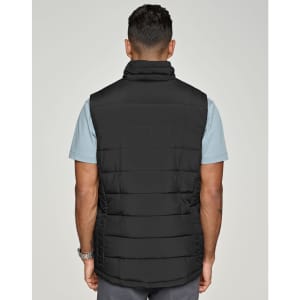 A black insulated puffer vest with a 3D cut, viewed from the back, worn over a light blue shirt.