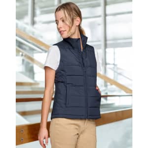 A navy insulated puffer vest with a 3D cut, featuring a zip front and side pockets, displayed on a model indoors.