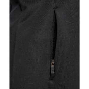 A close-up of a black softshell jacket featuring a zipped pocket. The fabric appears smooth and durable.