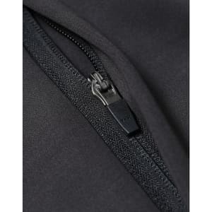 A close-up of a black softshell jacket featuring a zip with a branded pull tab.