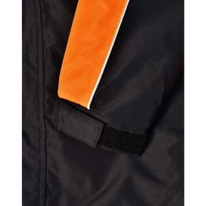 Close-up of a unisex jacket featuring black fabric with orange accents and a velcro cuff. Includes a branding logo.