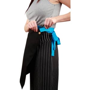 A woman adjusts a black canvas short waist apron with a blue tie, featuring a button and logo.