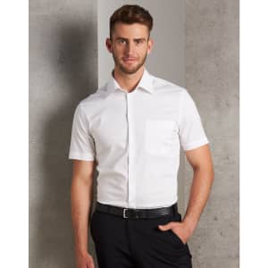 A short-sleeved white button-up shirt with a chest pocket, modelled by a man against a grey background.