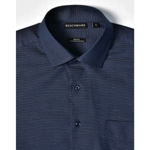 A navy blue button-up shirt featuring a pin dot pattern, with a single chest pocket and a branded label.