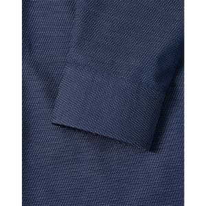 A close-up of a navy men's button-up shirt featuring a pin dot pattern and a cuff detail.