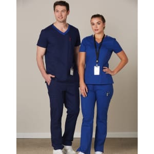 A navy blue and royal blue scrub top is worn by a model, featuring short sleeves and a logo.