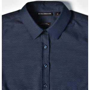 A navy blue pin dot stretch long sleeve shirt with a button-up collar and logo branding on the label.