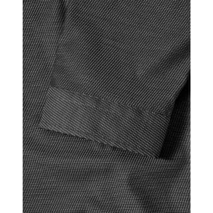 A close-up of a black pin dot stretch fabric with a 3/4 sleeve cuff of a button-up shirt. The shirt features a logo.