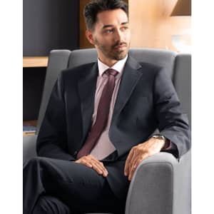 A men's two-button jacket in navy wool stretch, paired with a pink shirt and tie, displayed in a stylish setting.