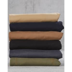A stack of men's chino pants in various colours: beige, navy, brown, black, dark grey, and green.