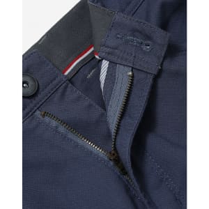 A close-up of navy blue ladies' chino pants featuring a zip fly and button closure, with a logo on the waistband.