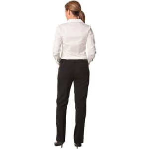 A woman stands facing away, wearing black low rise pants made from wool stretch, paired with a white shirt.