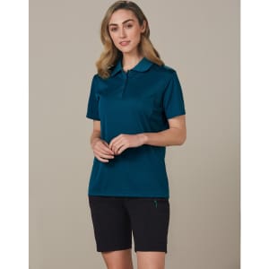 A model wearing dark cargo shorts and a teal polo shirt. The outfit includes a logo on the shirt.