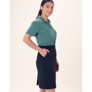 A woman is wearing a green polo shirt and a navy utility cargo skirt with pockets. The skirt has a fitted style.