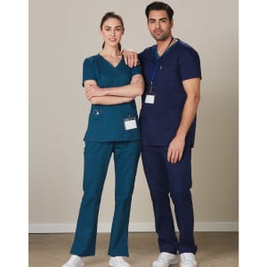 Two individuals wearing solid colour scrub pants—one in teal and the other in navy—standing side by side.