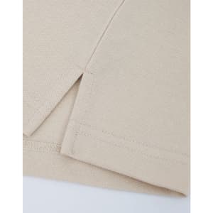 A close-up of a beige cotton/poly pique polo shirt, highlighting the stitched hem and sleeve detail.
