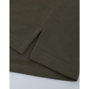 A close-up of a short-sleeved polo in an olive green cotton/poly pique fabric with a stitched hem.