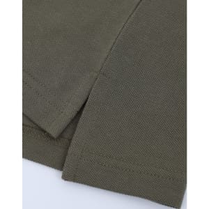 A close-up of olive green fabric with a textured surface, featuring the hem and sleeve of a polo shirt.