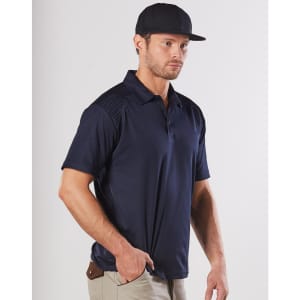A navy blue work polo shirt featuring textured shoulder panels and a logo. Worn by a man with a cap.