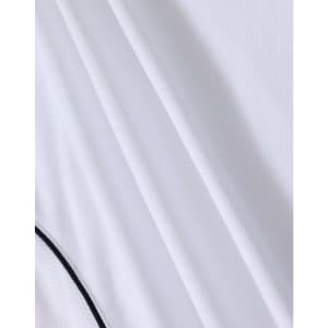 A white polo shirt with a textured fabric and contrasting detailing, featuring a logo.