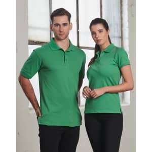 A green polo shirt featuring a logo, displayed on a male and female model against an industrial backdrop.