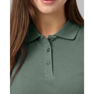 A close-up of a women's cotton stretch polo shirt in a muted green shade, featuring a classic collar and button detail.