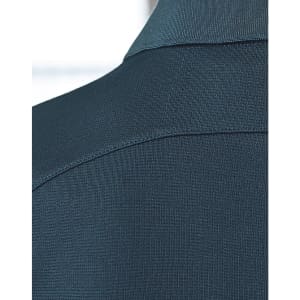 A close-up of a dark green polo shirt, featuring a textured fabric and a collar. The shirt has a logo present.