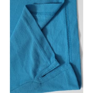 A close-up of a turquoise polo shirt featuring a fold at the sleeve and a branding logo.