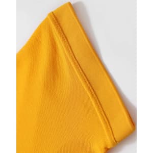 A close-up of a folded yellow polo shirt sleeve with a textured fabric detail. The shirt features a logo.