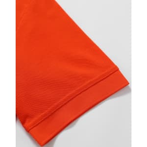 An orange polo shirt featuring a textured fabric and a folded sleeve hem. It includes a logo on the garment.