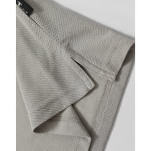A light grey polo shirt featuring detailed stitching and a branded label at the collar.