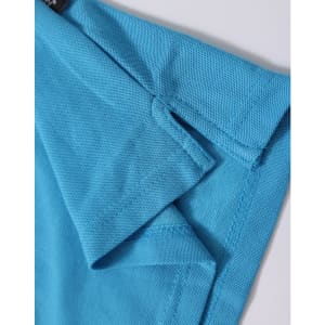 A close-up of a turquoise polo shirt, featuring a branded label and detailed fabric texture.