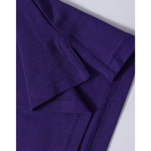 A close-up of a purple polo shirt, featuring a textured fabric and folded collar. The shirt has a logo.