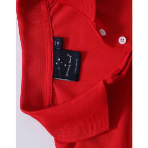 A red polo shirt featuring a collar and buttons, with a brand label on the inner neck area.