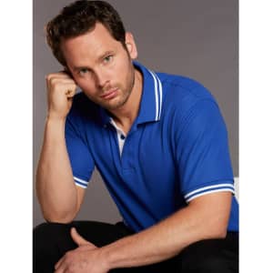 A blue polo shirt featuring white detailing on the collar and sleeves, modelled by a man.