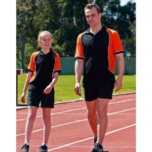 Men's TrueDry tri-colour short-sleeve pique polo in black and orange, paired with matching shorts, worn by two people on a track.