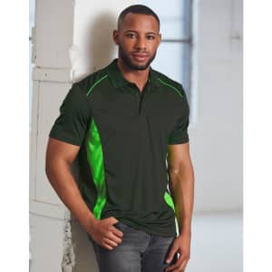 A man wears a dark green polo shirt featuring bright green contrast detailing and a logo. The background is a bright, industrial space.
