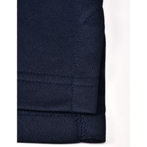 A close-up of a navy blue sustainable poly/cotton polo shirt sleeve with stitching details. It has a logo.