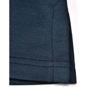 A close-up of a dark navy polo shirt, featuring a textured fabric and a neatly stitched hem. The shirt has a logo.