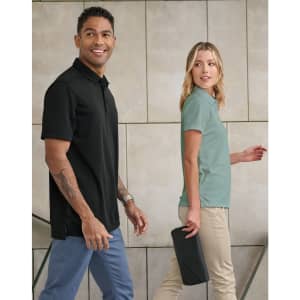 A black men's polo and a green women's polo are worn by two people against a neutral background. Both garments have logos.