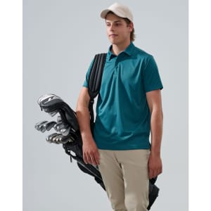 A man wearing a teal polo shirt holds a golf bag with clubs, dressed in light trousers and a cap.