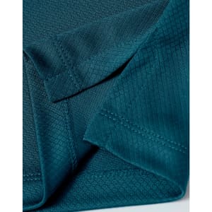 Close-up of a teal sustainable jacquard knit fabric, showcasing the texture and stitching detail of a polo shirt.