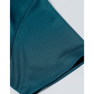 A close-up of a teal sustainable jacquard knit fabric, showcasing the texture of a short-sleeved polo.