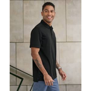 A man wearing a black short-sleeve polo shirt stands against a textured wall, showcasing a sleek design and fit.